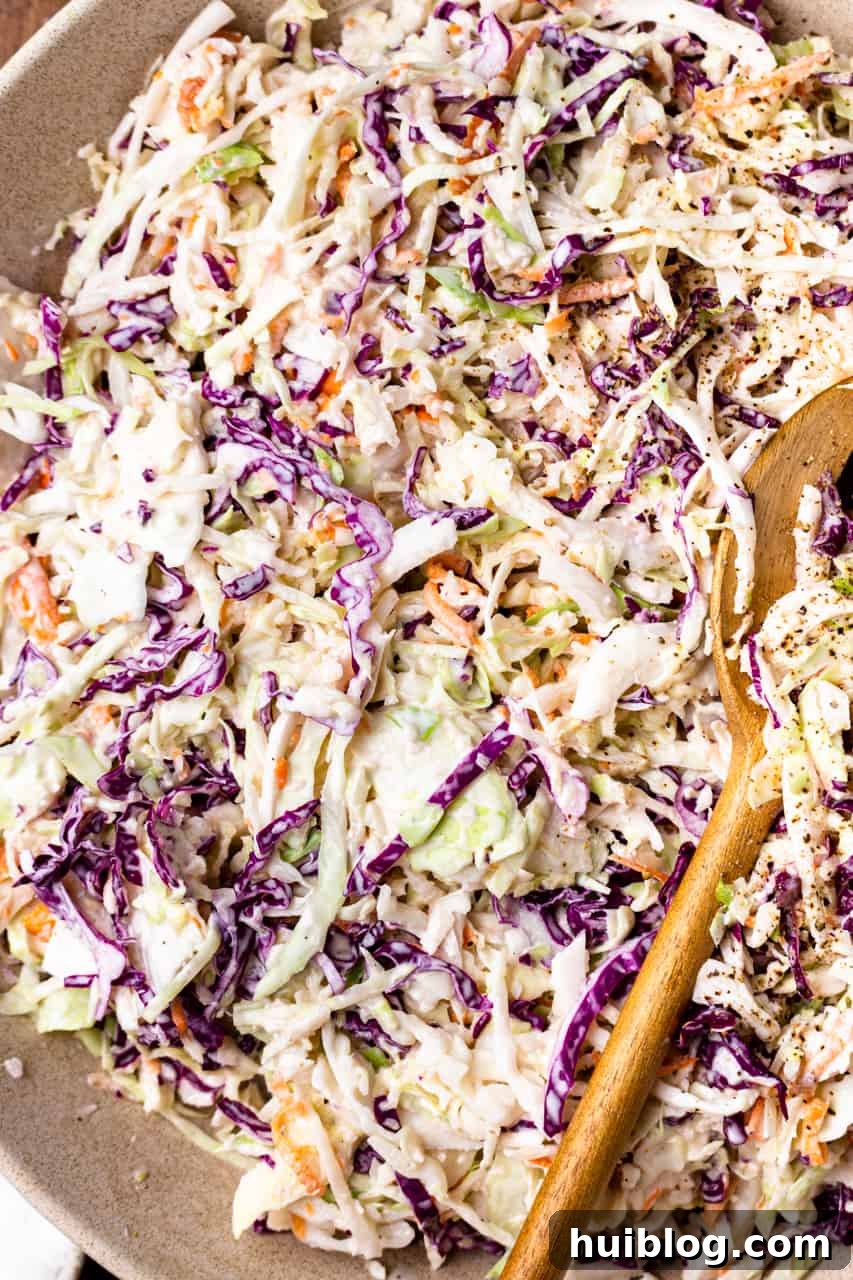 Effortless Slow Cooker BBQ Pulled Chicken 13 Up close view of mixed together coleslaw being served with wooden spoons.