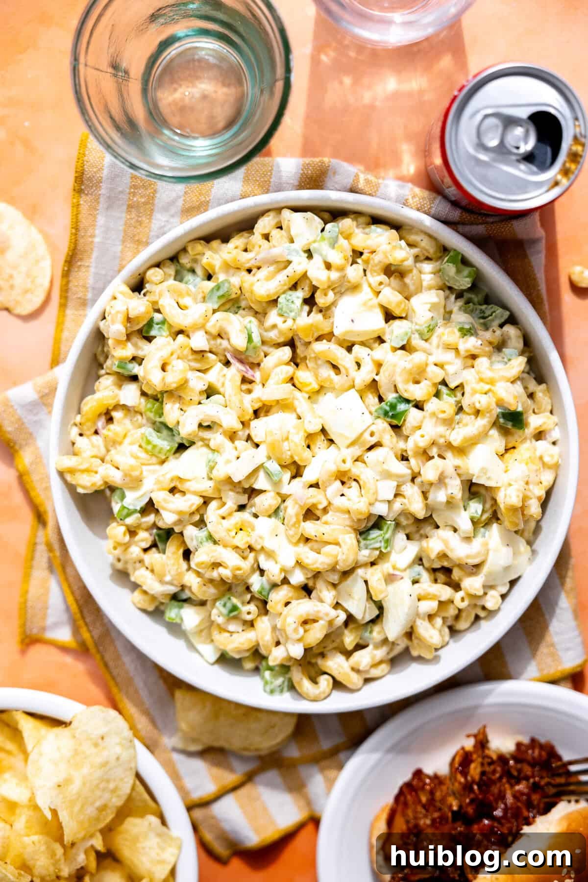 Effortless Slow Cooker BBQ Pulled Chicken 14 Bowl of macaroni salad on a picnic table with chips and pulled pork nearby.