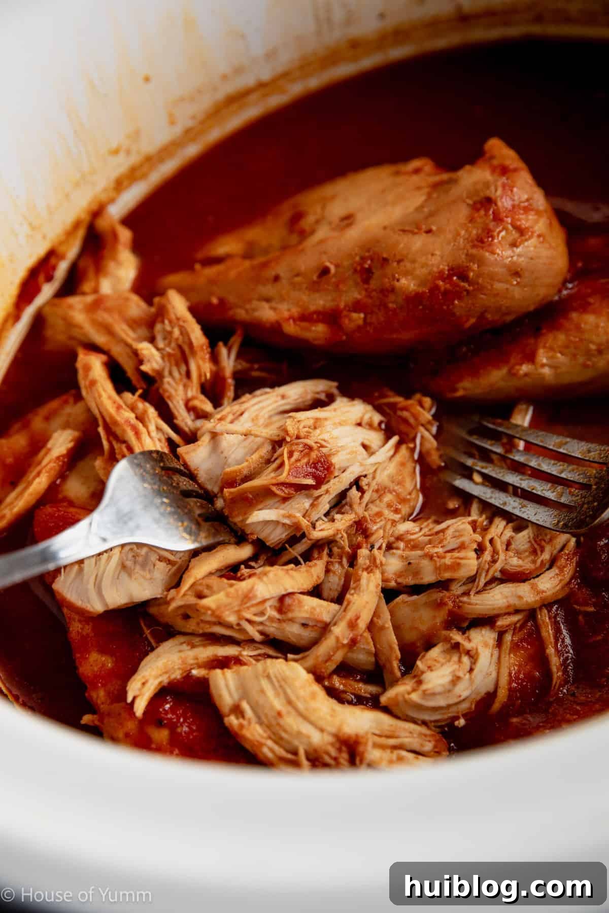 Effortless Slow Cooker BBQ Pulled Chicken 8 Shredding chicken in a slow cooker with two forks.