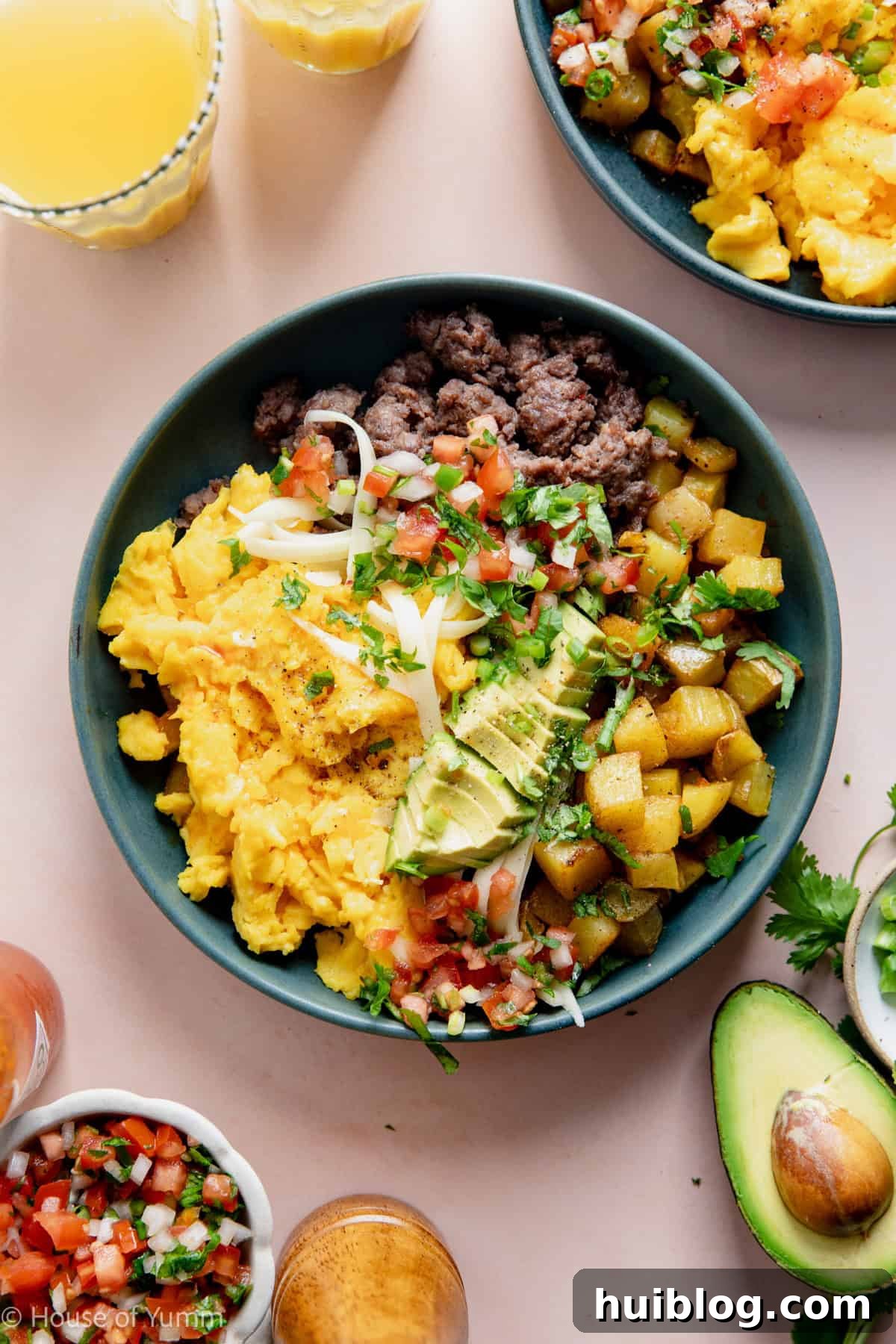 Breakfast burrito bowl made with scrambled eggs, sausage, and potatoes, topped with avocado and salsa.