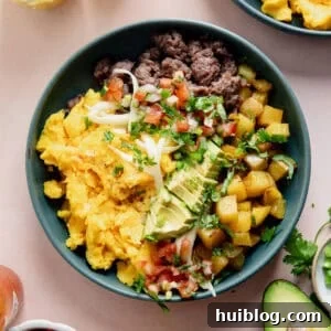 Breakfast burrito bowl made with scrambled eggs, sausage, and potatoes, topped with avocado and salsa.