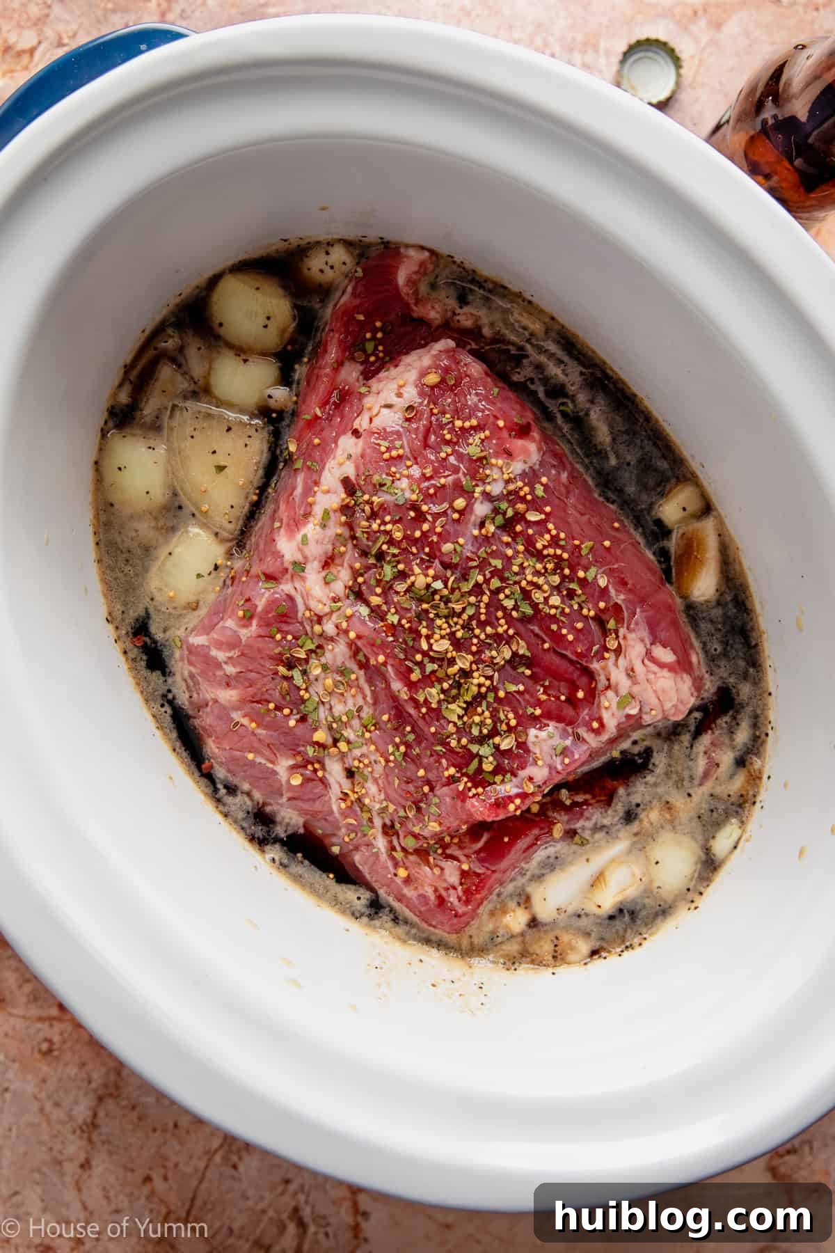 corned beef added to a slow cooker with seasonings, broth, and guiness beer. 