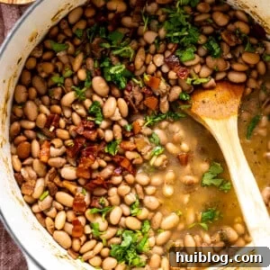Pot of charro beans topped with cilantro and crispy bacon.