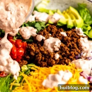 Dressing being drizzled on taco salad.