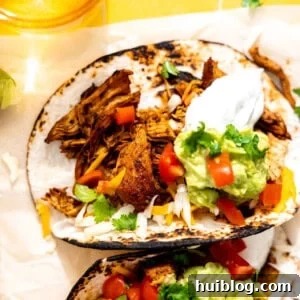 Chicken tacos served with sour cream, guacamole, and diced tomatoes.