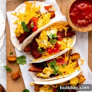 Tray of Breakfast tacos loaded with eggs, bacon and potatoes served with salsa.