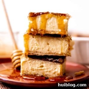 Stack of sopapilla cheesecake bars being drizzled with honey.