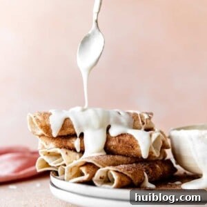Stack of cinnamon tortillas being drizzled with cream cheese glaze.